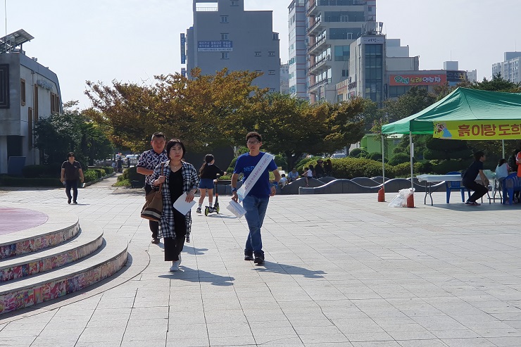 홍보 전단지 배부 후 손님과 함께 부스로 돌아오고 있는 모습