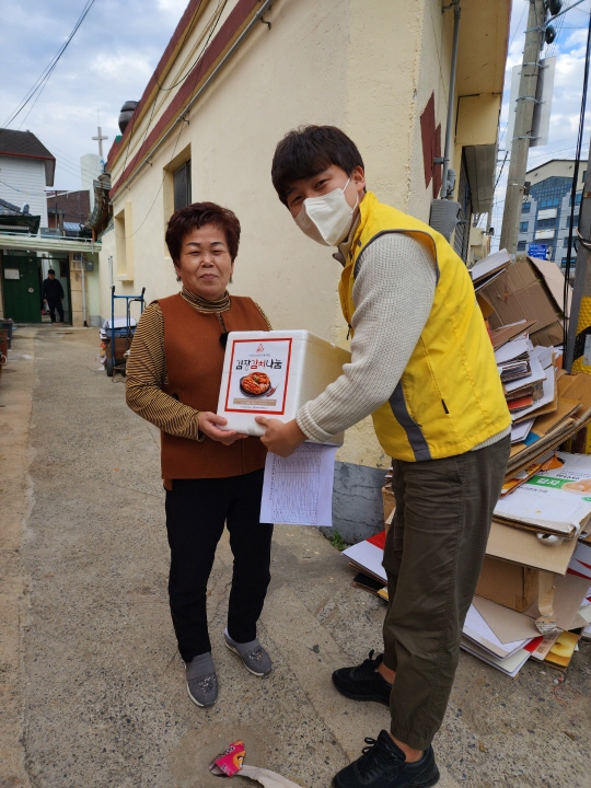 사진설명입니다. 김장김치를 지역사회주민에게 전달하고 있는 MSY봉사회원의 모습입니다