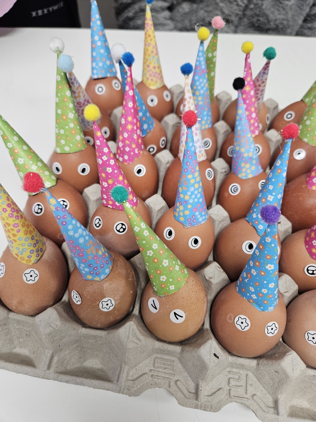 삶은 달걀에 고깔을 붙이고 다양한 모양의 눈 스티커를 붙여 꾸민 달걀을 찍은 사진입니다. 