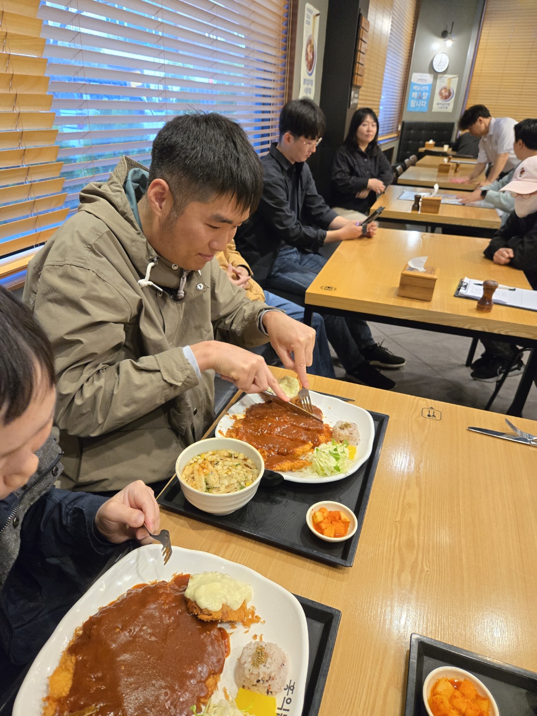 주문한 돈가스를 자르고 있는 취업자의 사진입니다. 