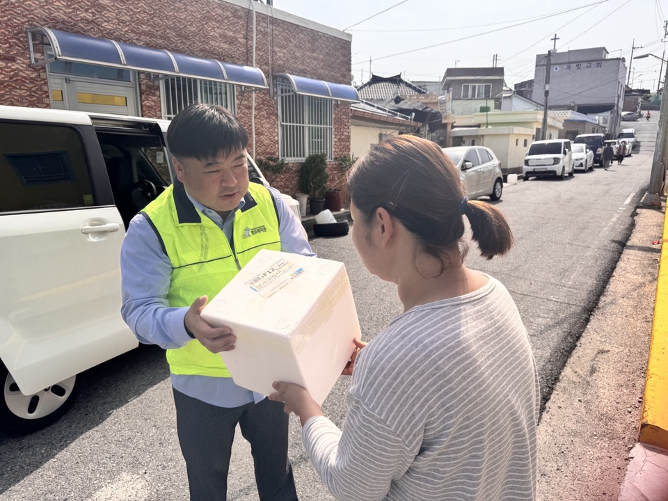 담당 사회복지사가 이용인에게 김치를 전달하고 있는 사진입니다.