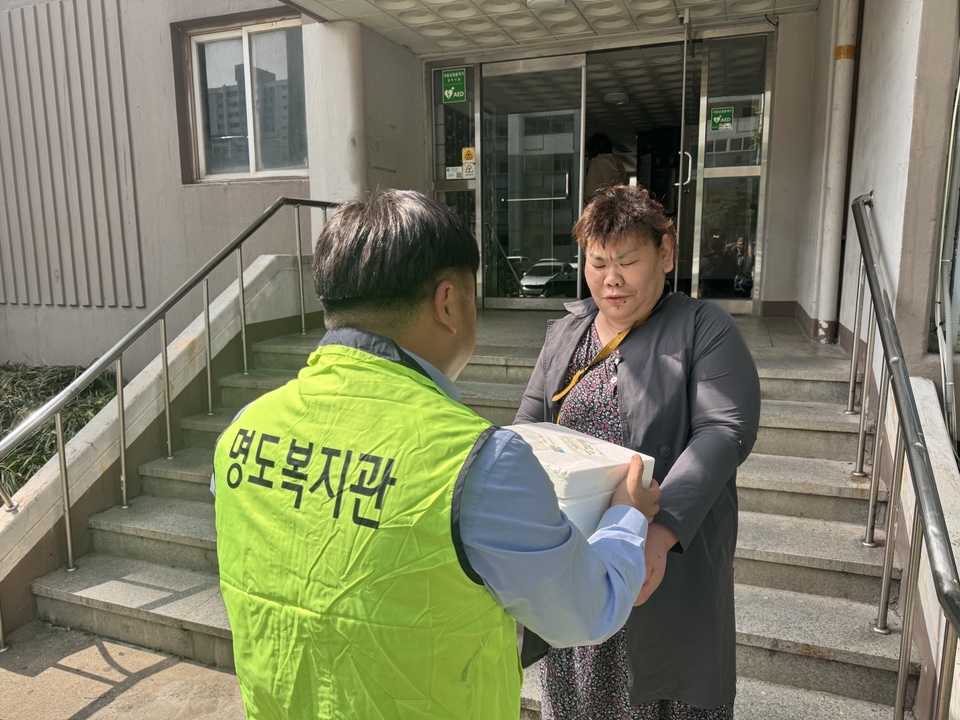 담당 사회복지사가 이용인에게 김치를 전달하고 있는 사진입니다.