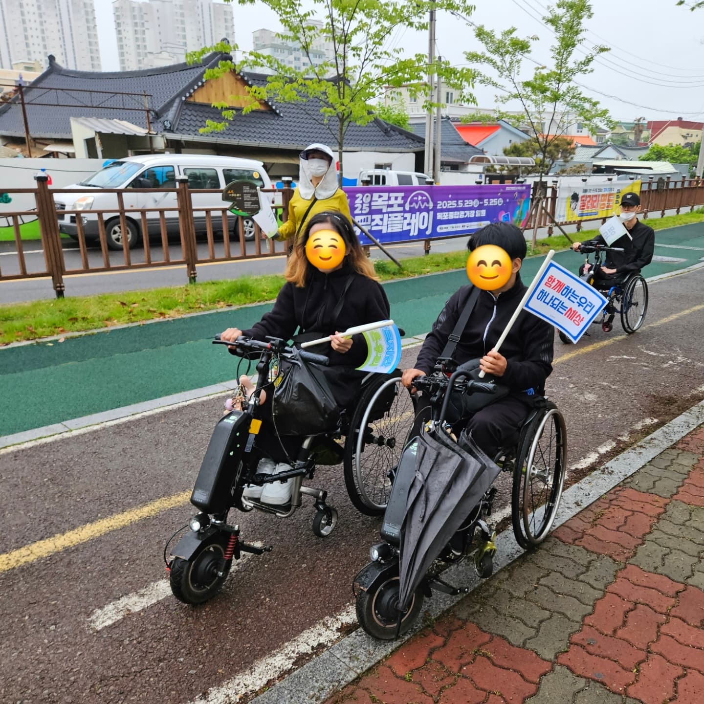 휠체어를 탄 두명의 지체장애인이 함께하는 우리, 하나되는 세상이라고 적힌 깃발을 들고 휠체어를 타고 있는 모습의 사진입니다. 