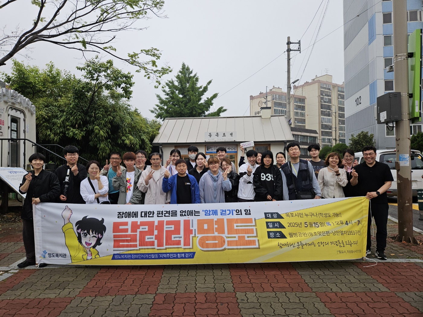 '달려라명도' 현수막을 들고 명도복지관 담당자들과 참여자, 봉사자들이 함께 찍은 단체사진입니다. 