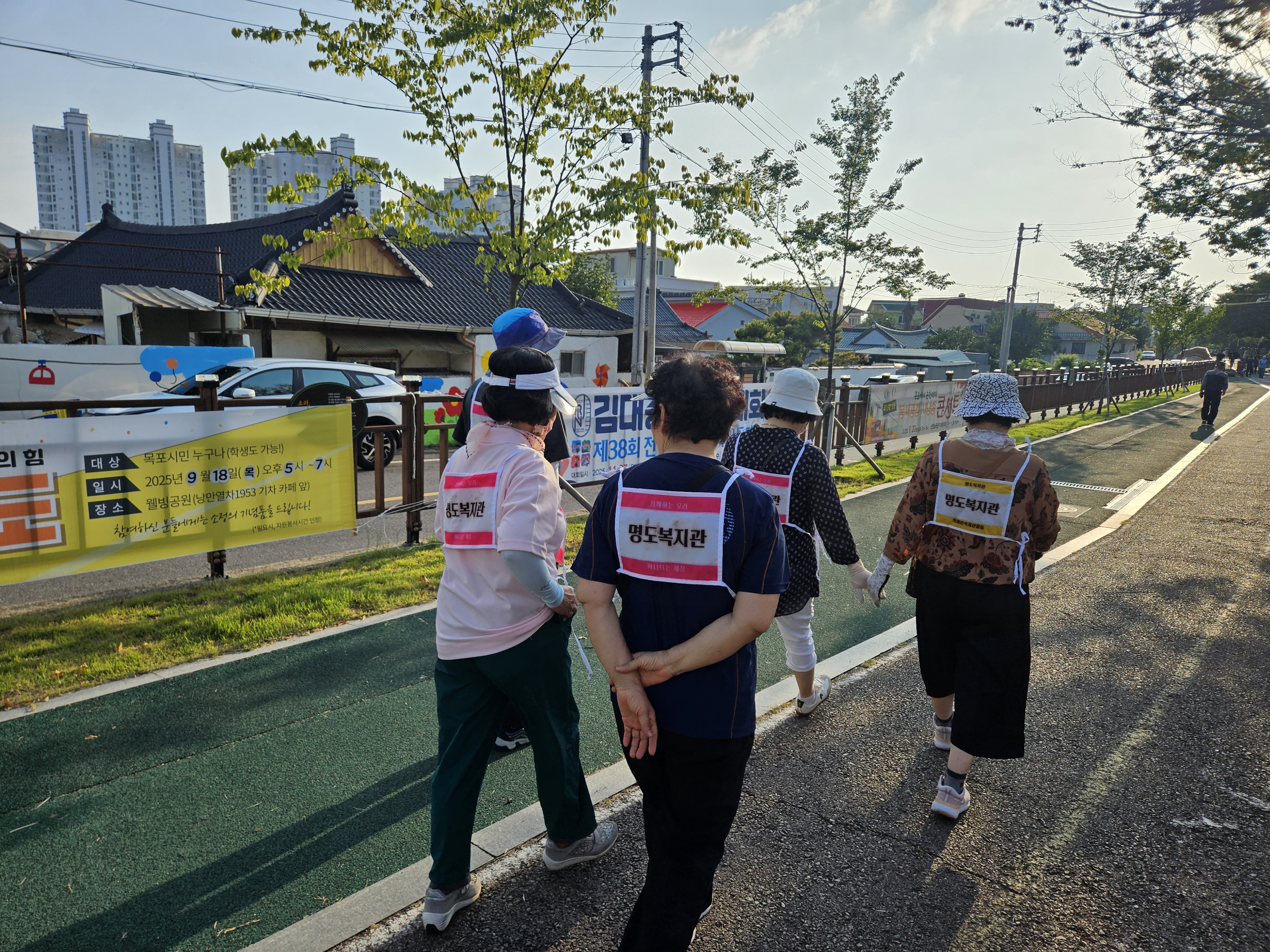 명도복지관, 우리, 하나 등이 적힌 배번호를 메고 지인들과 함께 걷고 있는 지역주민의 모습입니다.