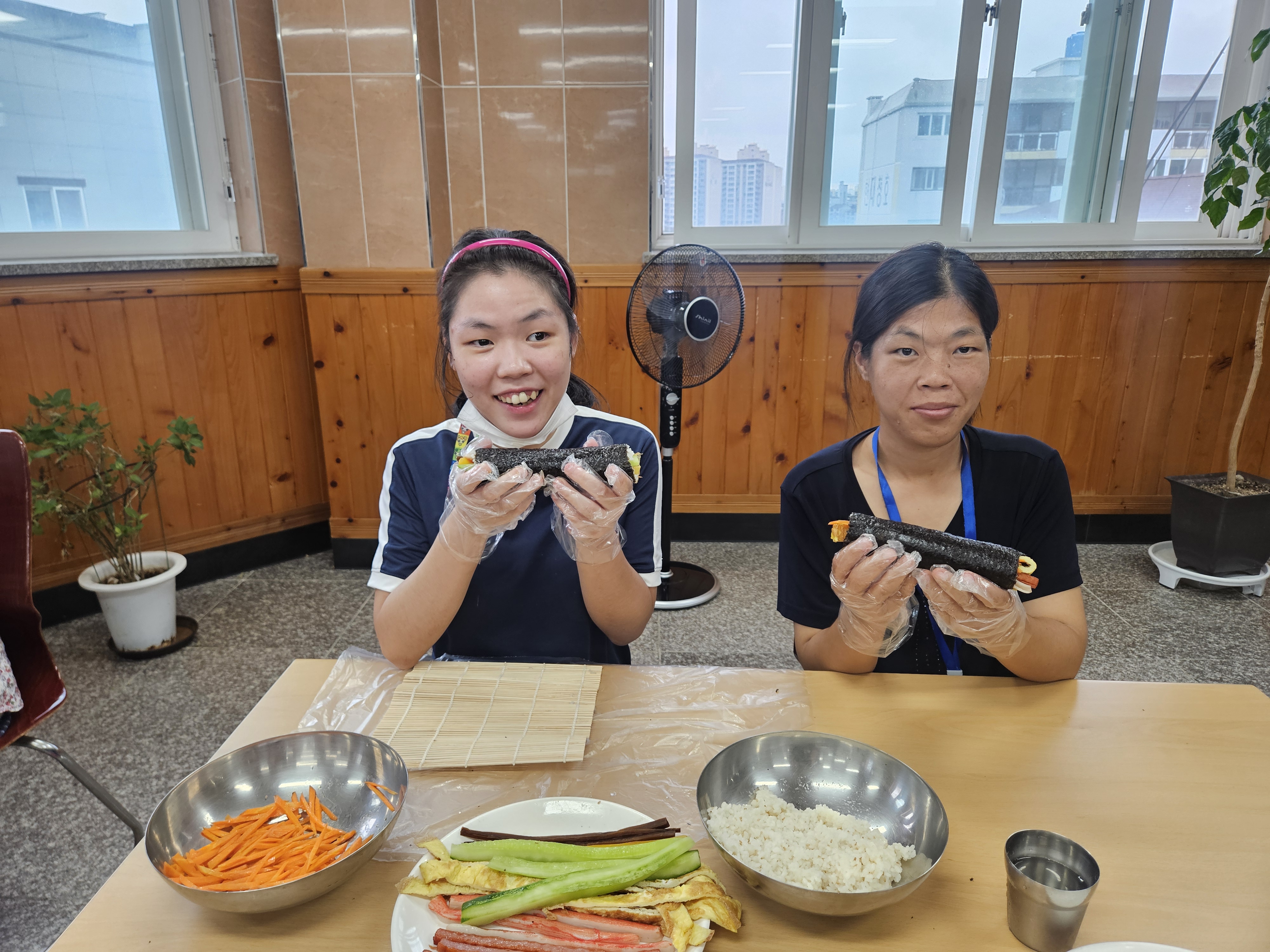 자신이 만든 김밥을 들고 밝은 표정으로 촬영한 참여자 두분의 사진입니다. 