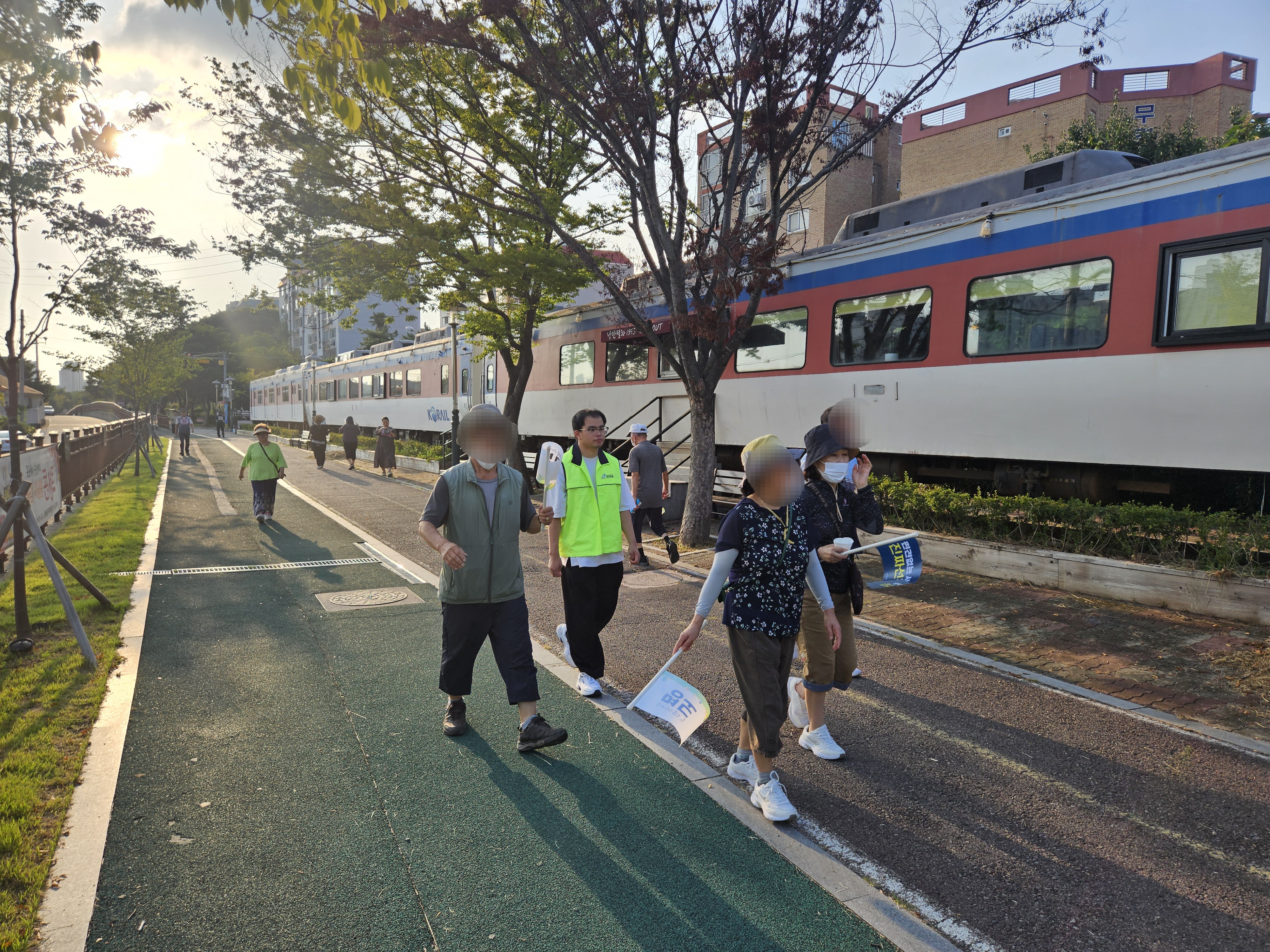 장애인식개선 메세지가 담긴 깃발을 들고 지인들과 함께 걷고 있는 지역주민의 모습입니다.