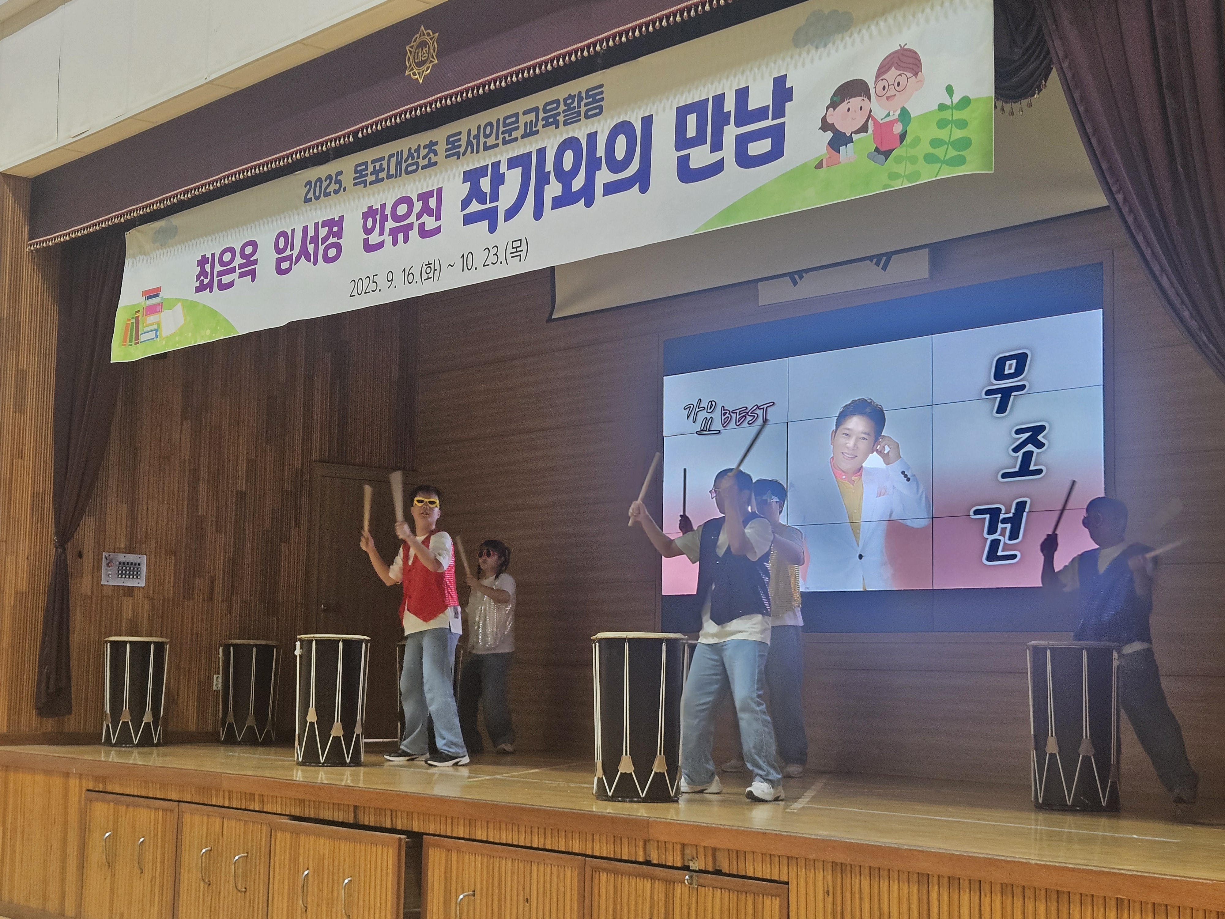 학교 강당에서 난타공연을 하고 있는 리듬공감팀의 사진입니다.