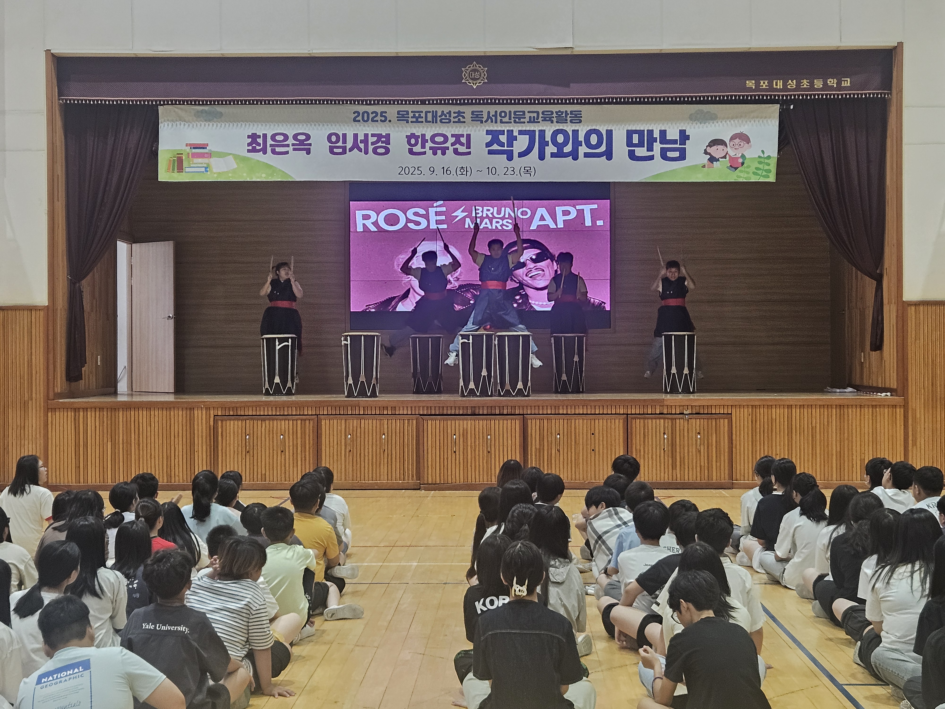 학교 강당에서 난타공연을 하고 있는 리듬공감팀의 사진입니다.