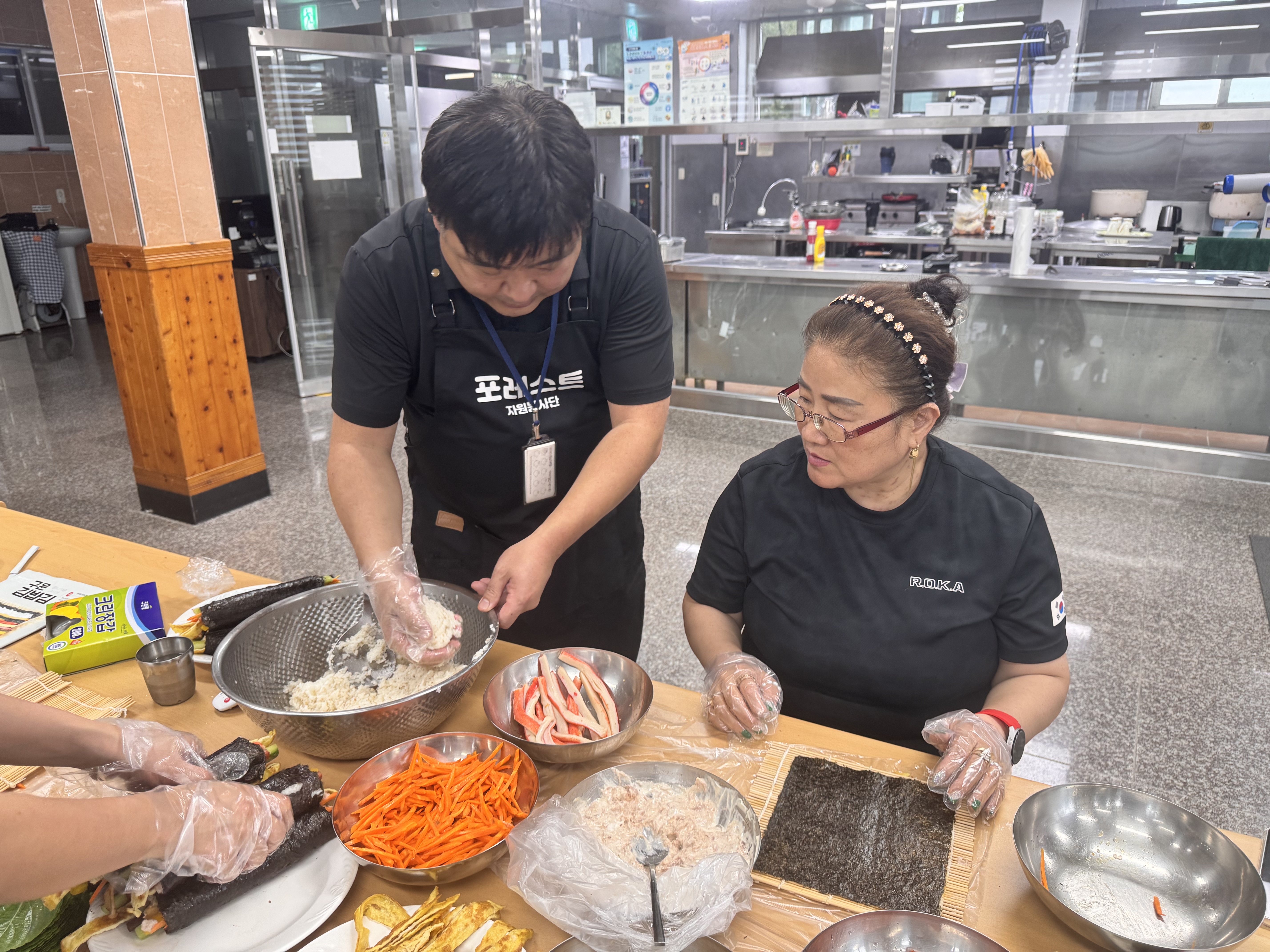 참여자와 담당자가 함께 김밥을 싸고 있는 사진입니다.