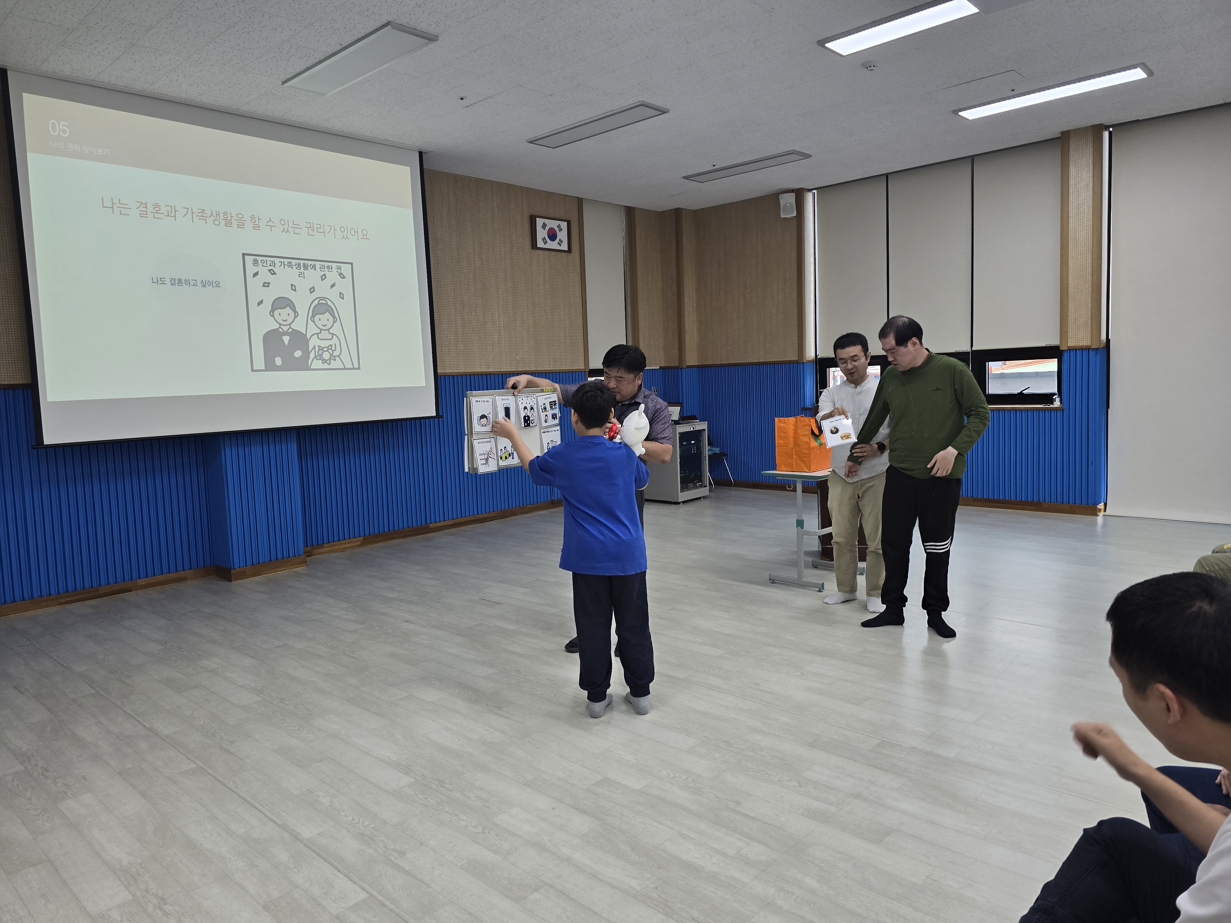 이용인들이 앞으로 나와 칠판에 붙여져 있는 보완대체의사소통(AAC)를 활용하여 자신의 권리를 직접 선택하고 있는 모습입니다.