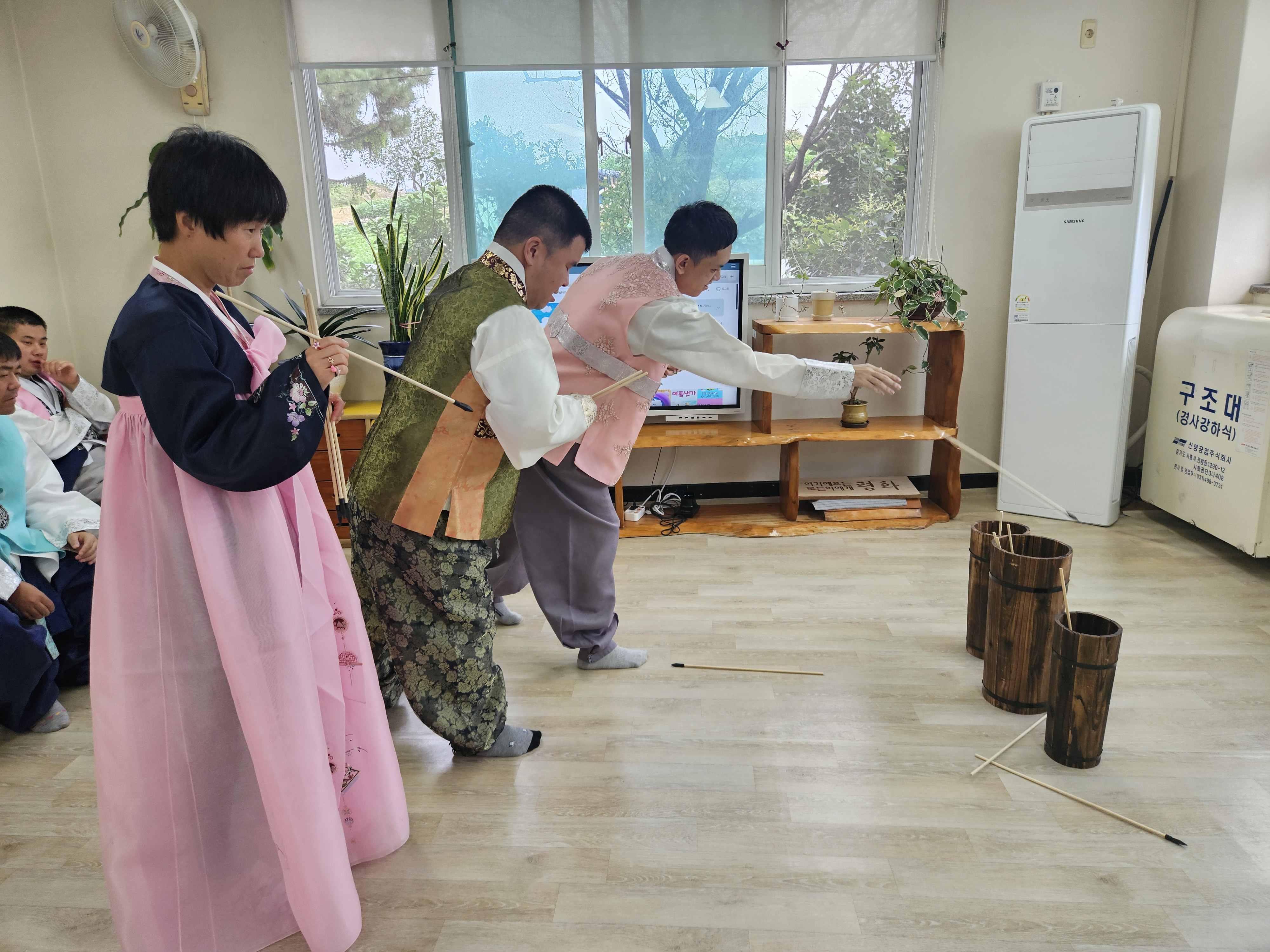 곱게 한복을 차려입은 이용인들이 투호를 던지고 있는 사진입니다.