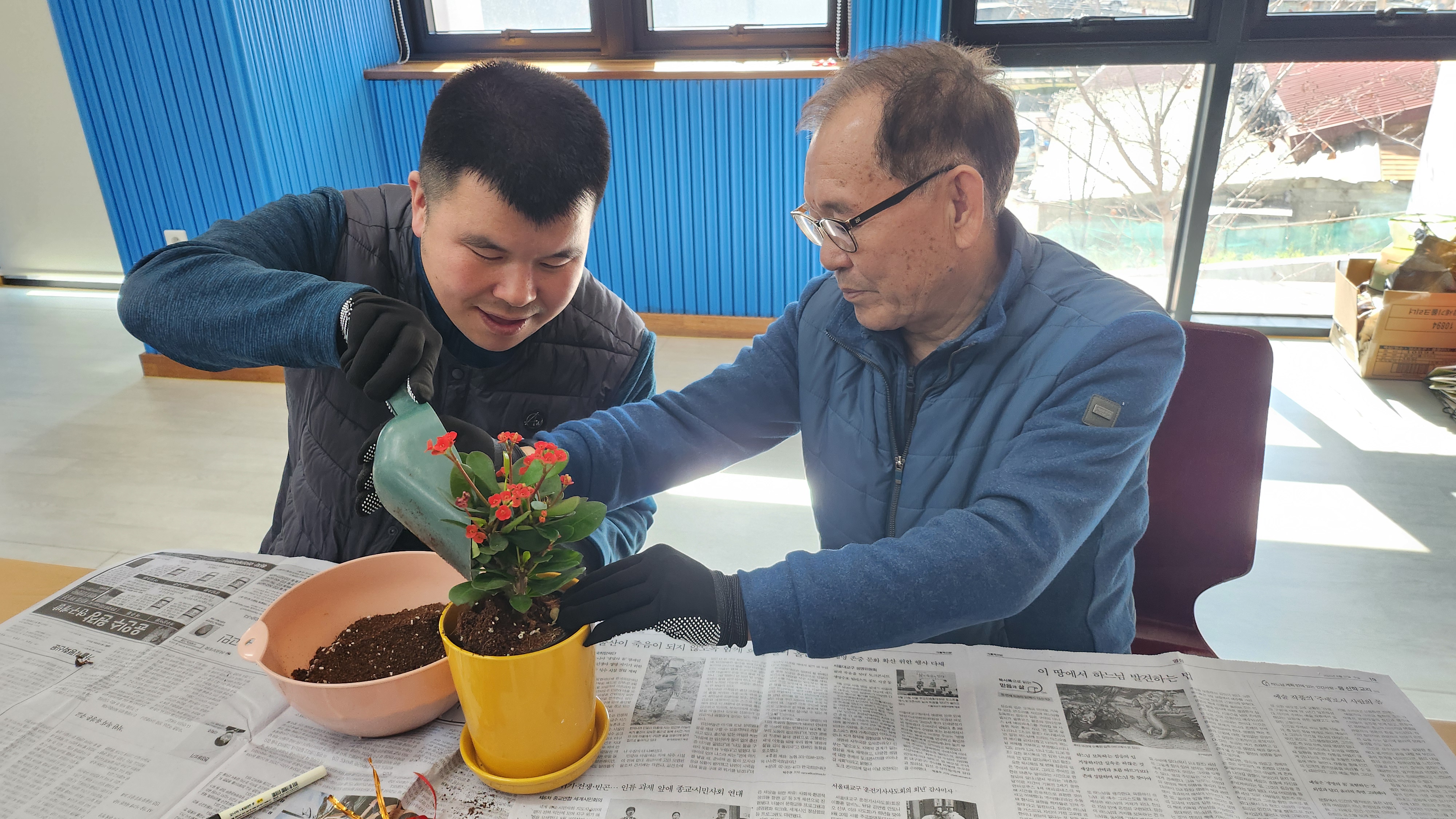 주간보호센터 이용인분과 보호자분이 화분에 함께 흙을 담고 있는 사진입니다.