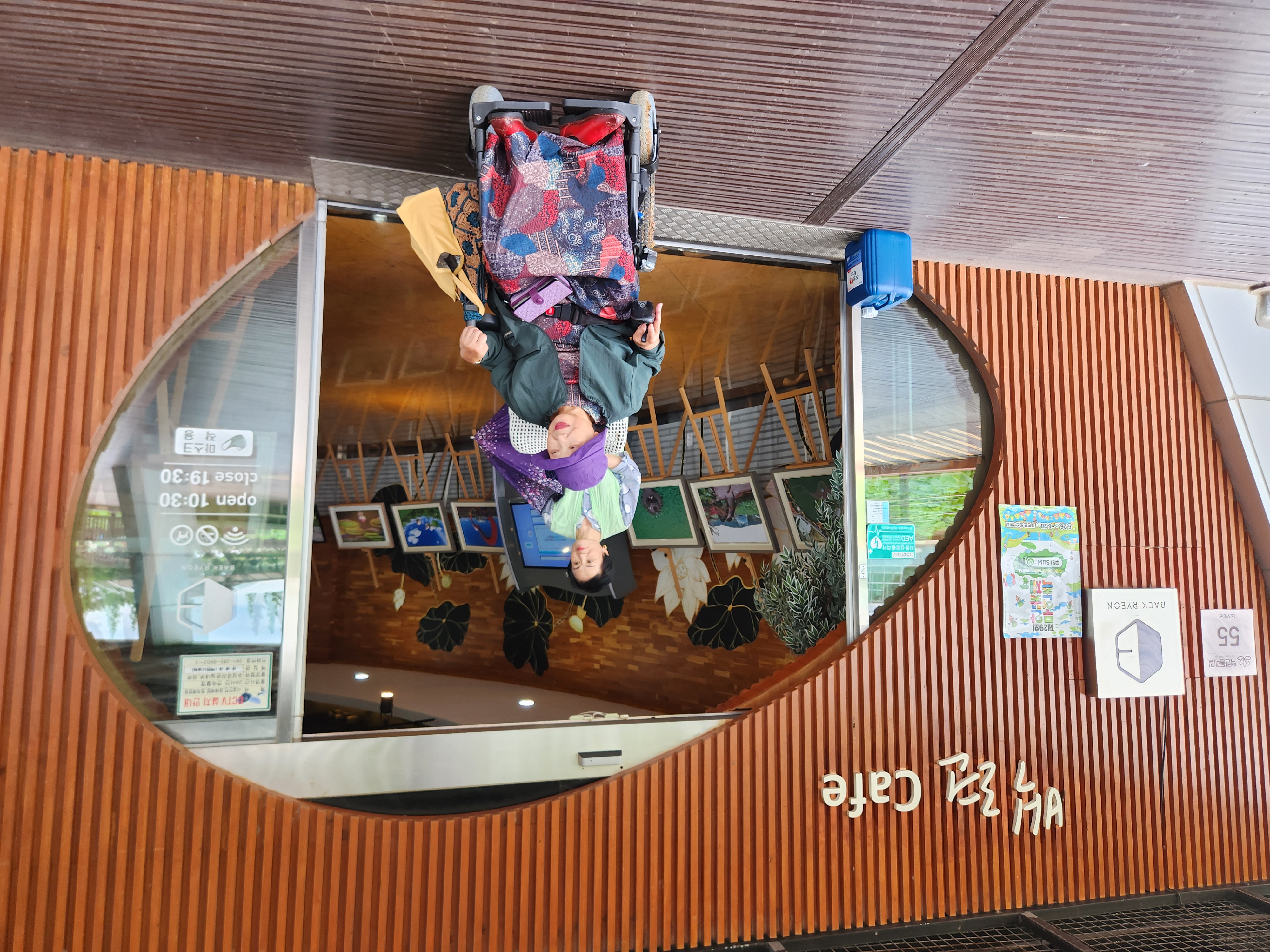 무안회산백련지 백련카페 앞에서 활동보조선생님과 휠체어를 탄 재가장애인이 함께 사진을 찍는 모습입니다.