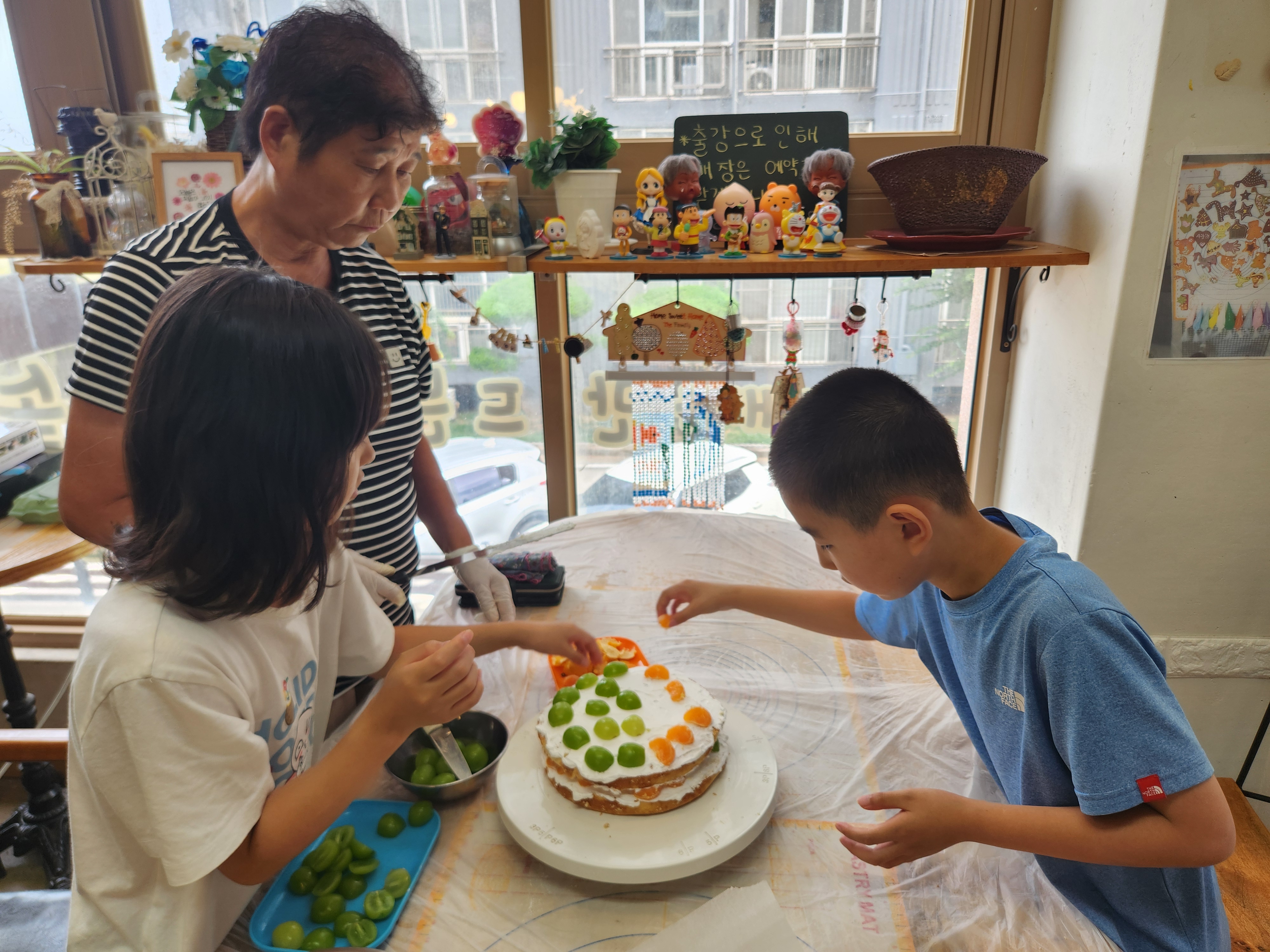 할머니와 손자녀가 함께 케이크를 만들고있는 모습입니다.